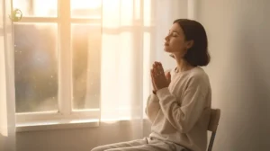 Woman praying with a rosary beside an open Bible and candle, seeking healing, comfort, and strength for a loved one